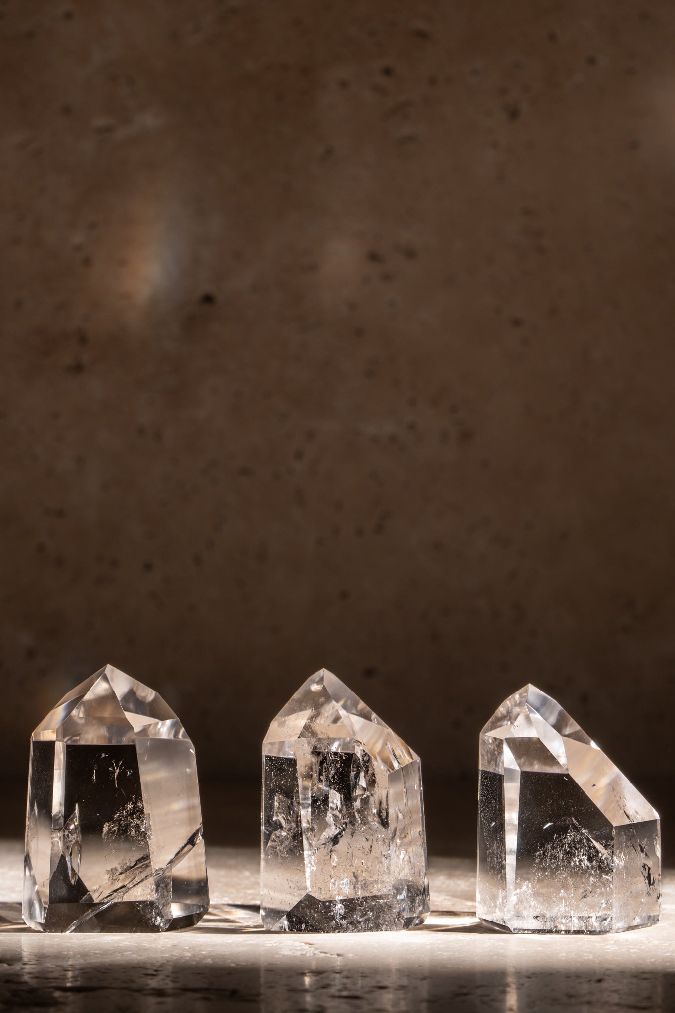 A set of three polished AAA quality Clear Quartz towers with sharp, faceted tips, displaying clear surfaces and natural inclusions.