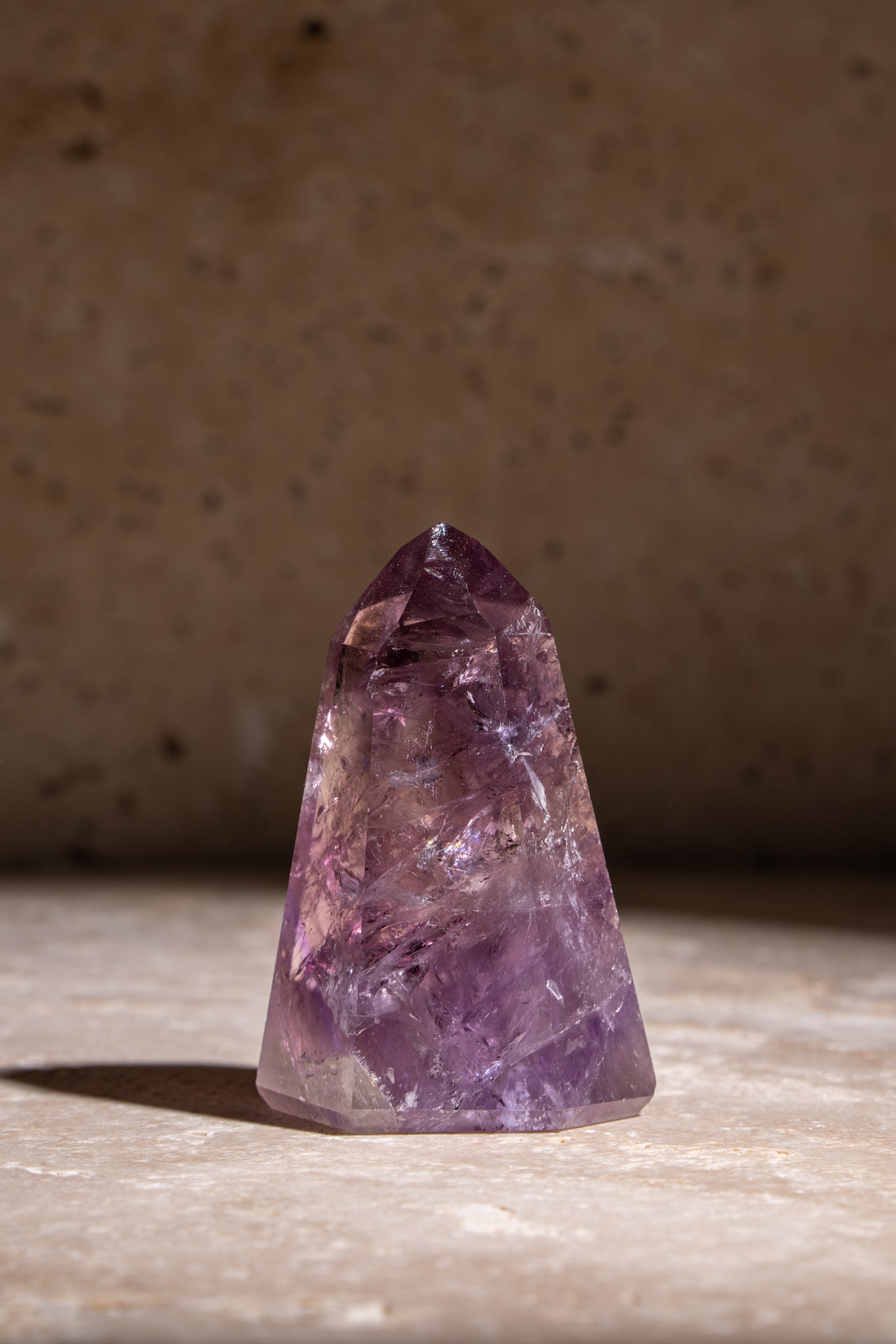 A polished Amethyst tower showcasing deep purple hues with natural inclusions, reflecting the crystal's energy and beauty.