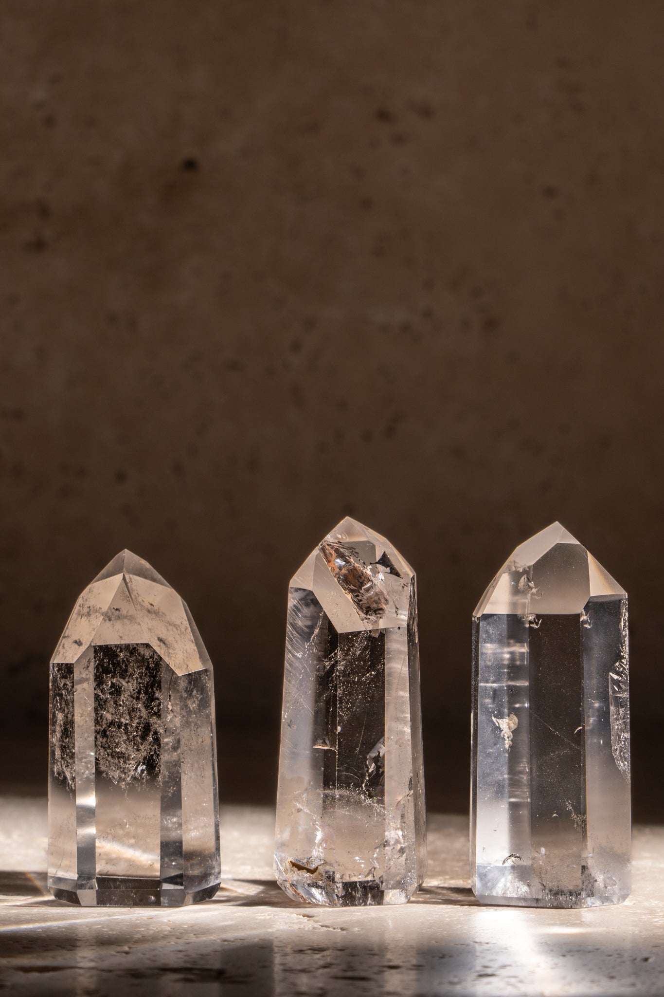 A set of three polished AAA quality Clear Quartz towers with sharp, faceted tips, showcasing brilliant clarity and smooth surfaces.