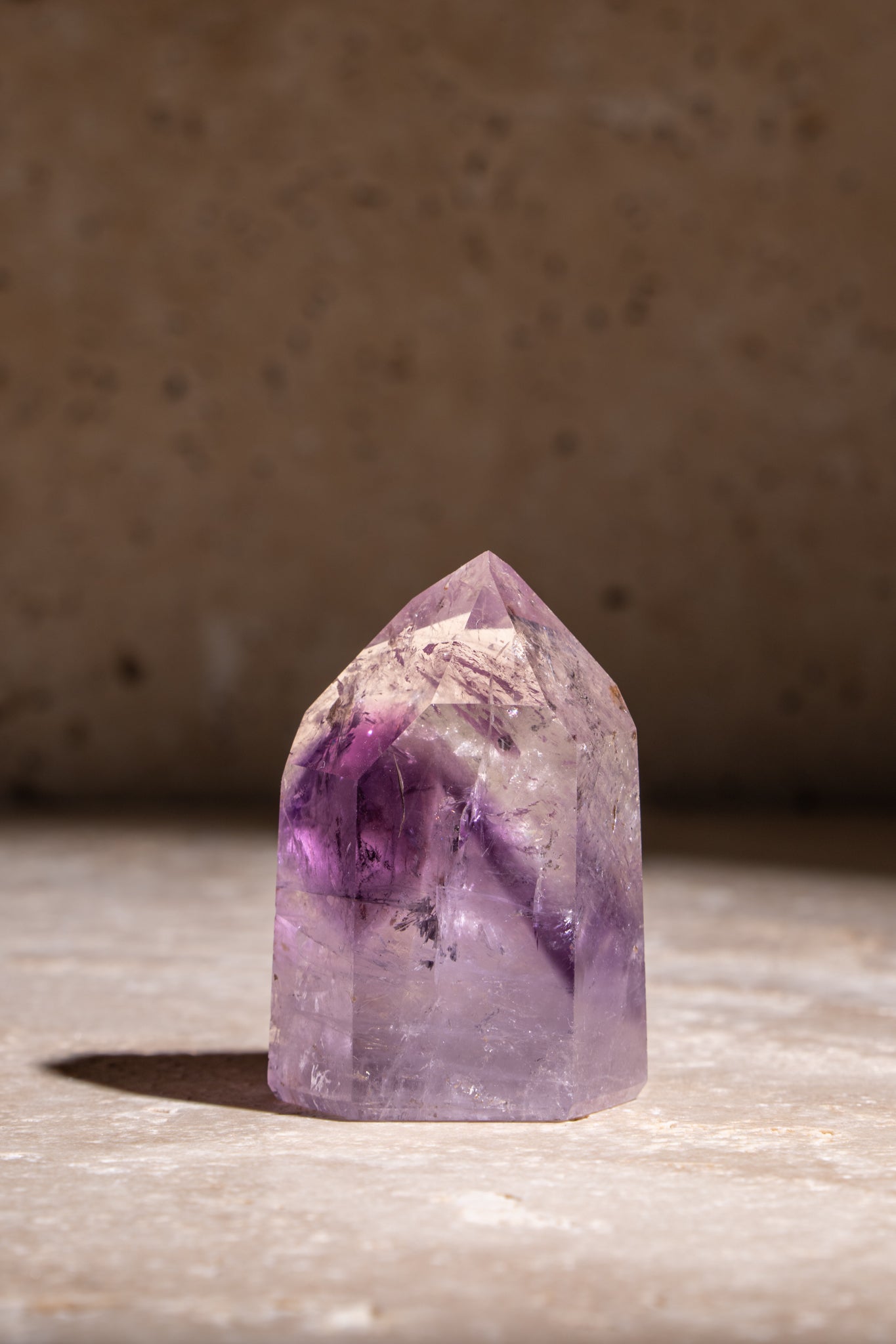 A polished Amethyst tower showcasing deep purple hues with natural inclusions, reflecting the crystal's energy and beauty.
