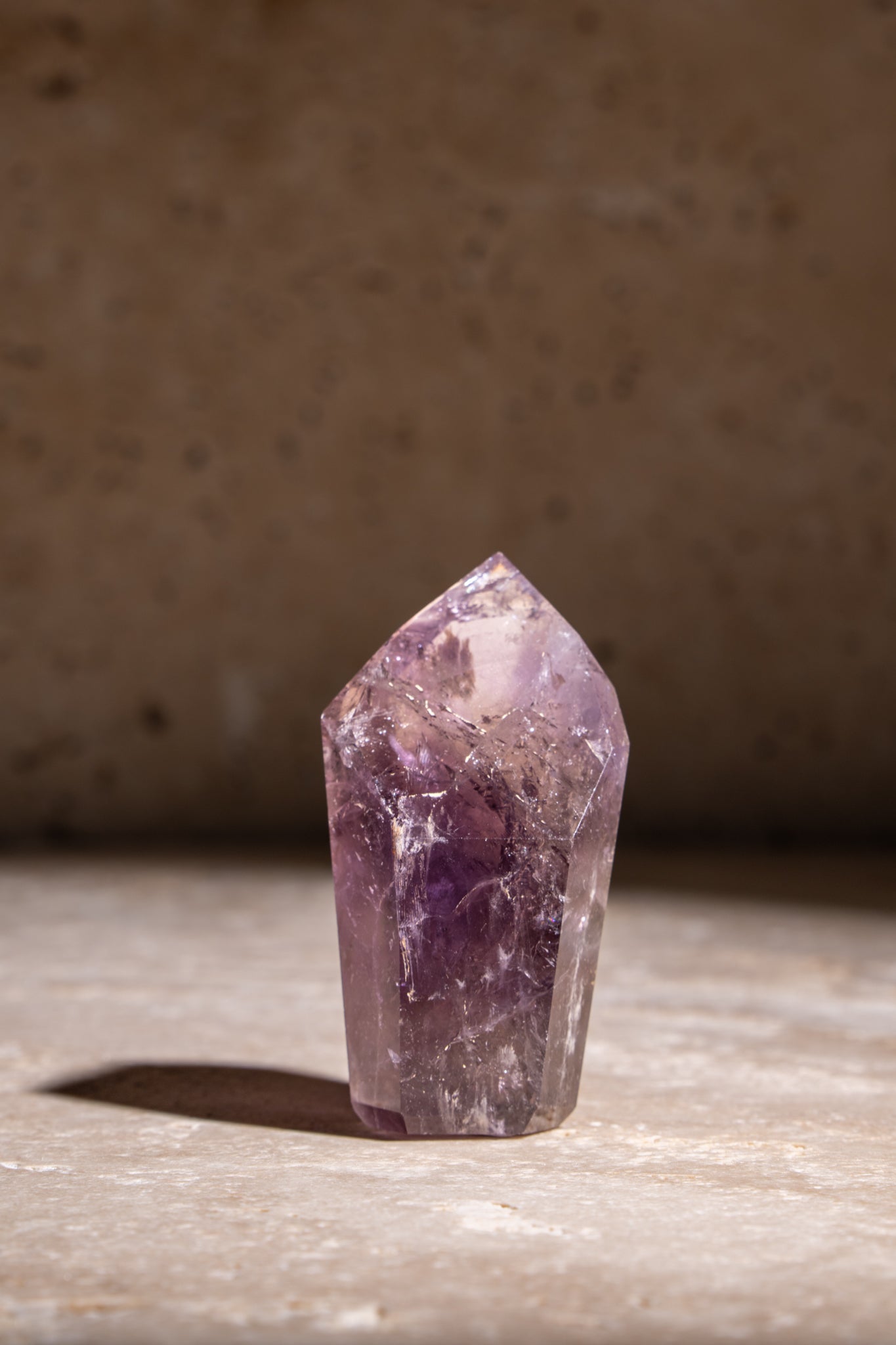 A polished Amethyst crystal tower with deep purple hues and visible natural inclusions, adding a calming and healing energy.