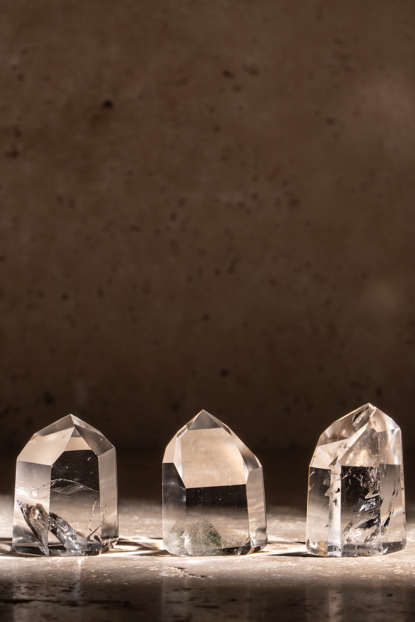 A set of three polished AAA quality Clear Quartz towers with sharp, faceted tips, showcasing exceptional clarity and natural inclusions.