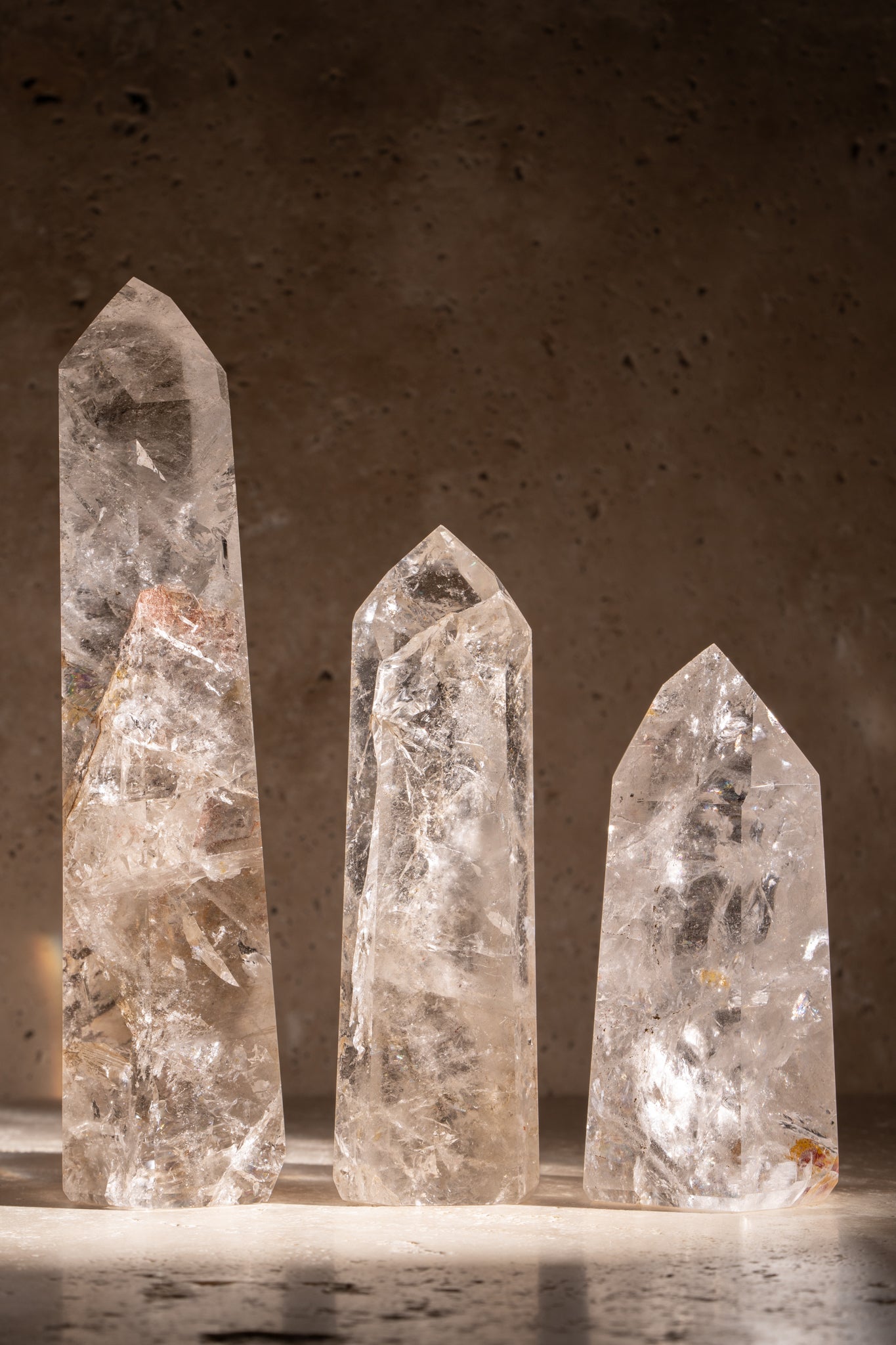 A set of three polished AAA quality Clear Quartz towers with sharp, faceted tips, showcasing exceptional clarity and natural inclusions.