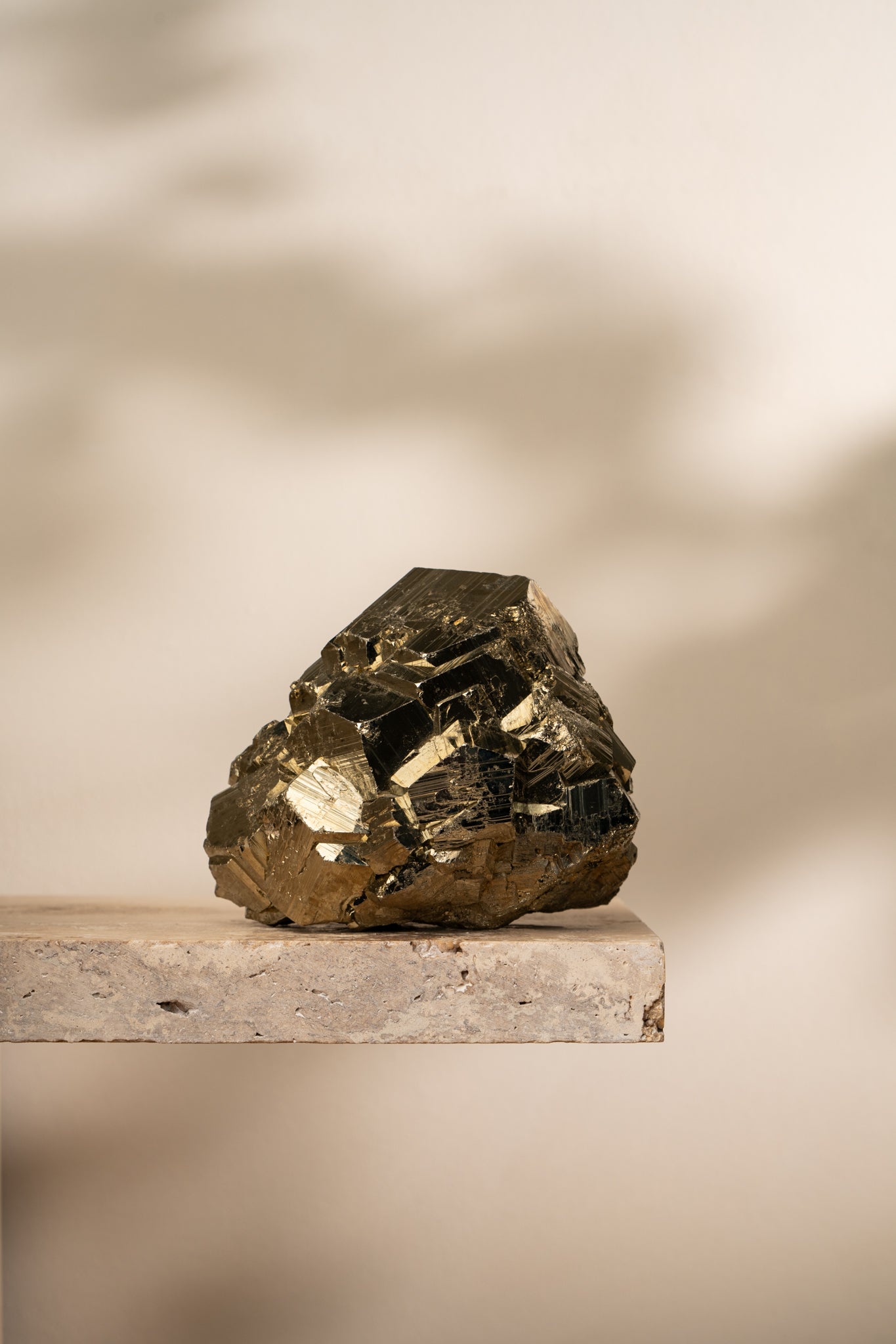 A raw Pyrite formation featuring large, well-defined cubic structures with a brilliant gold metallic luster, resting on a neutral stone surface.