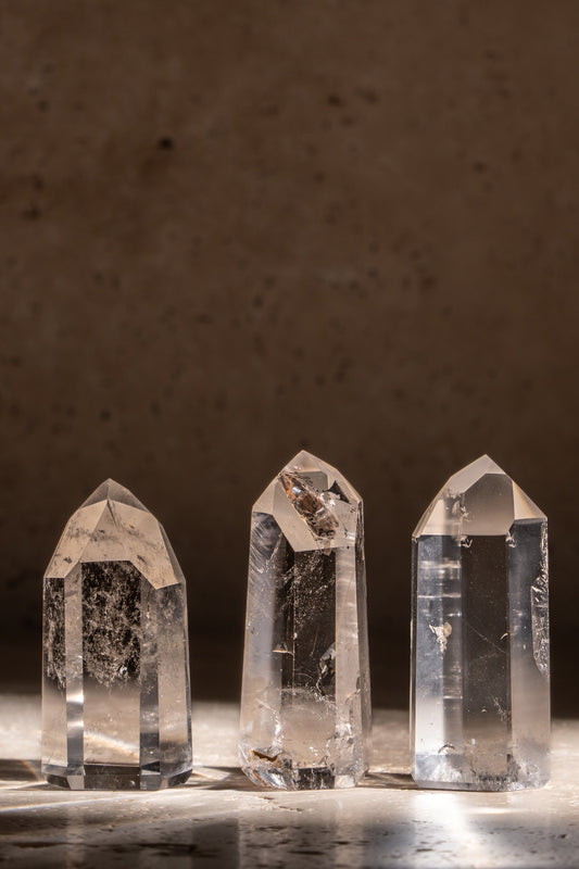 A set of three polished AAA quality Clear Quartz towers with sharp, faceted tips, showcasing brilliant clarity and smooth surfaces.