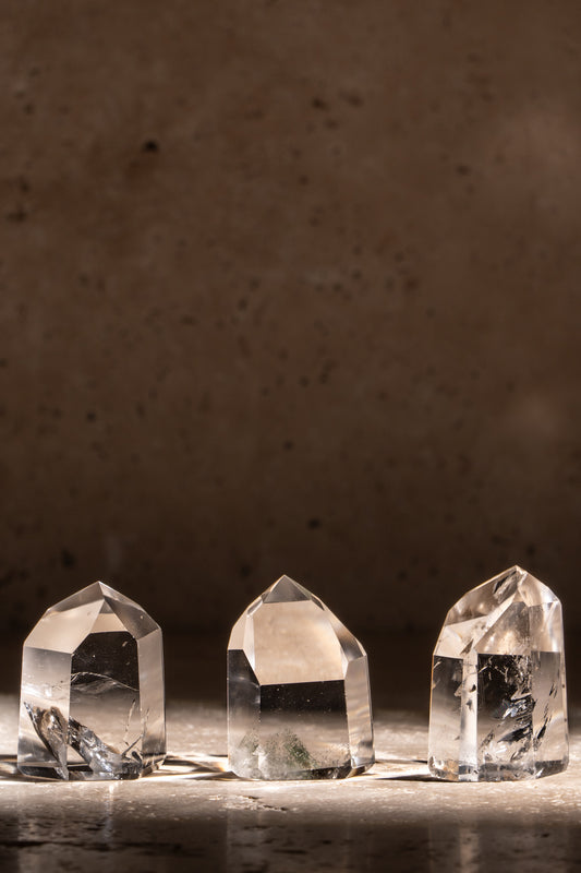 A set of three polished AAA quality Clear Quartz towers with sharp, faceted tips, showcasing exceptional clarity and natural inclusions.