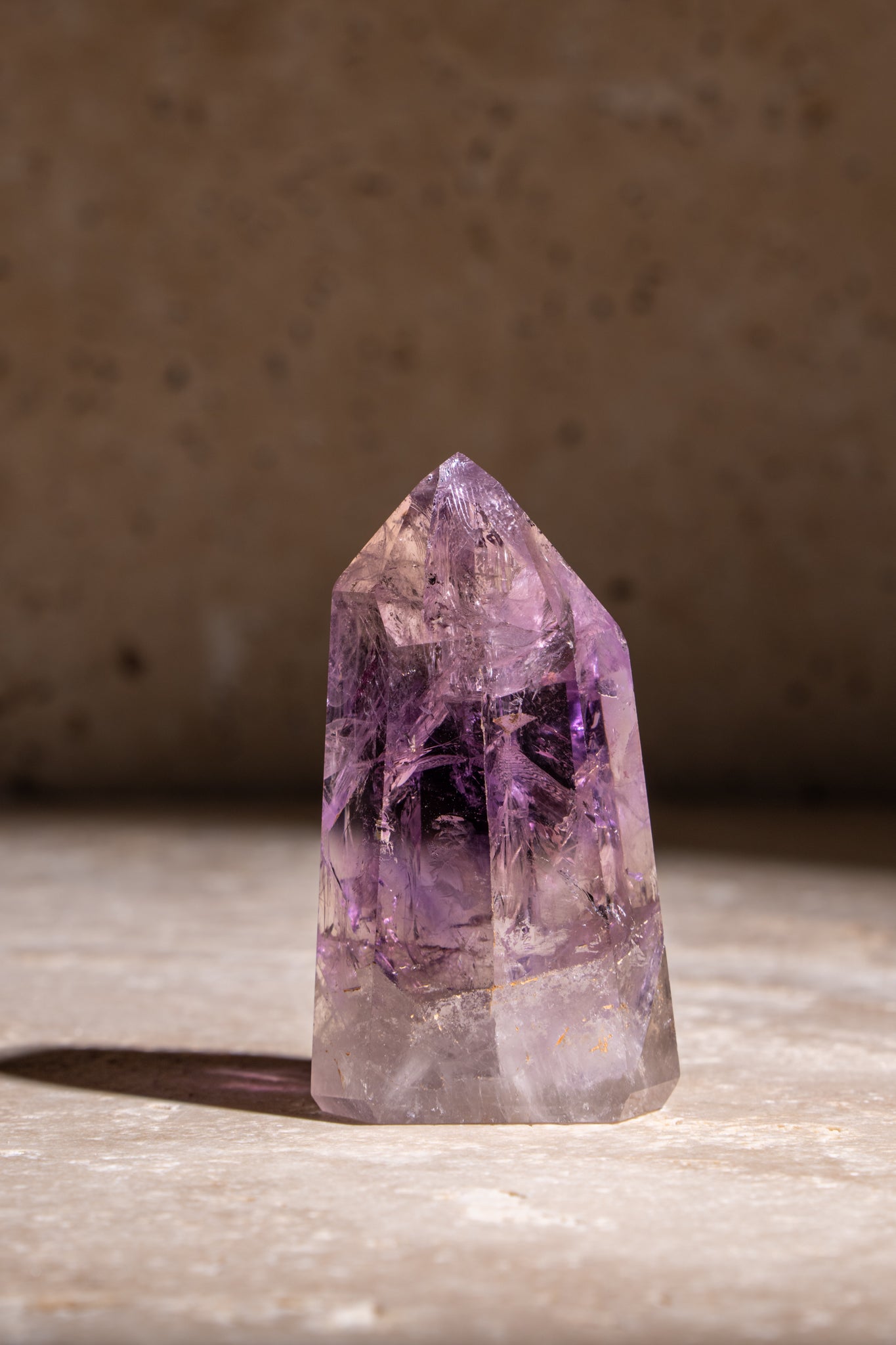 A polished Amethyst crystal tower with shades of purple and natural inclusions, offering healing and calming properties.