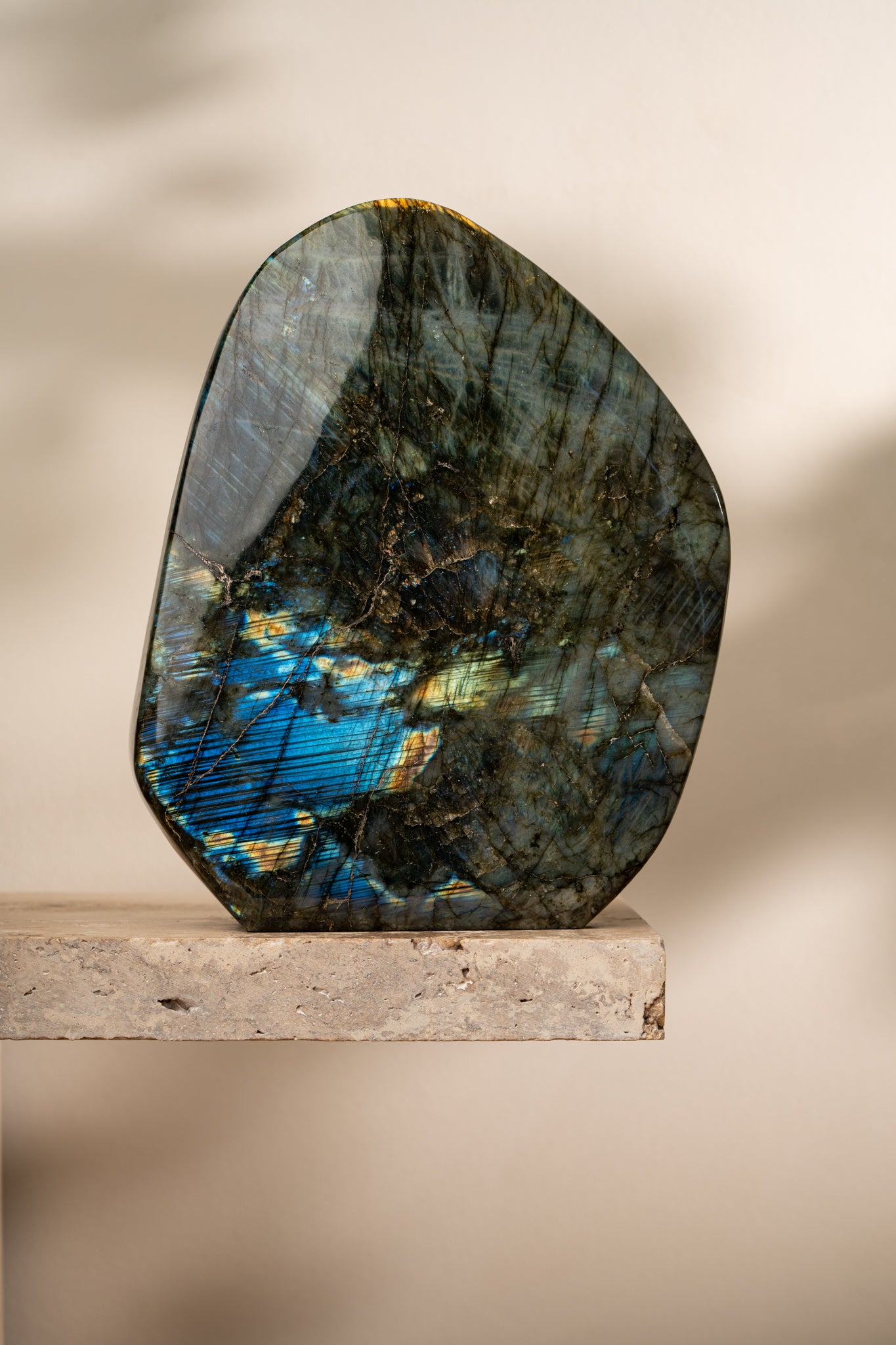 A large, dark-toned polished Labradorite with an intense electric blue flash, highlighting its natural patterns and iridescence.