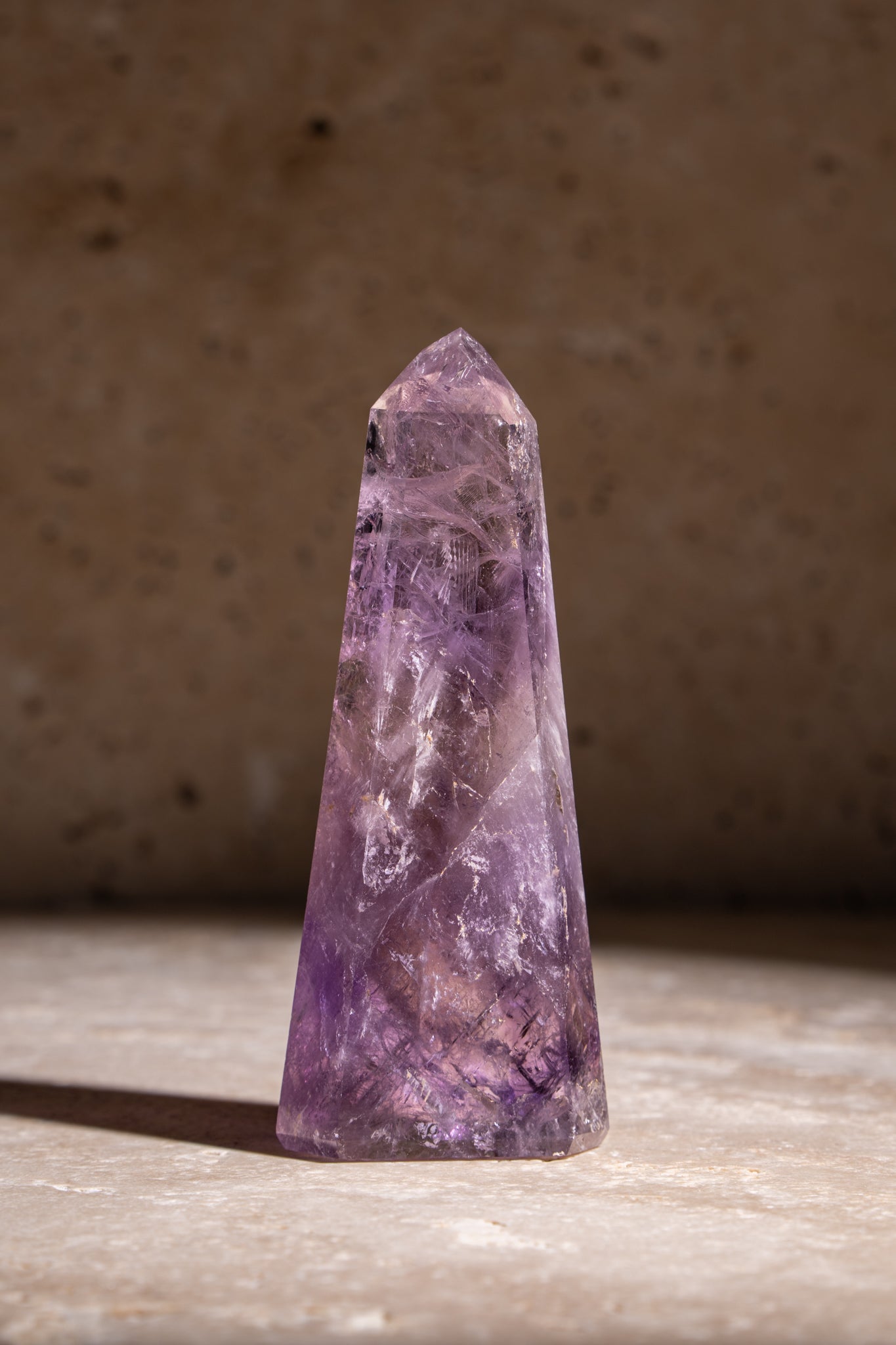 A single tall Amethyst crystal point with sharp edges and stunning purple hues, featuring natural inclusions for a unique appearance.