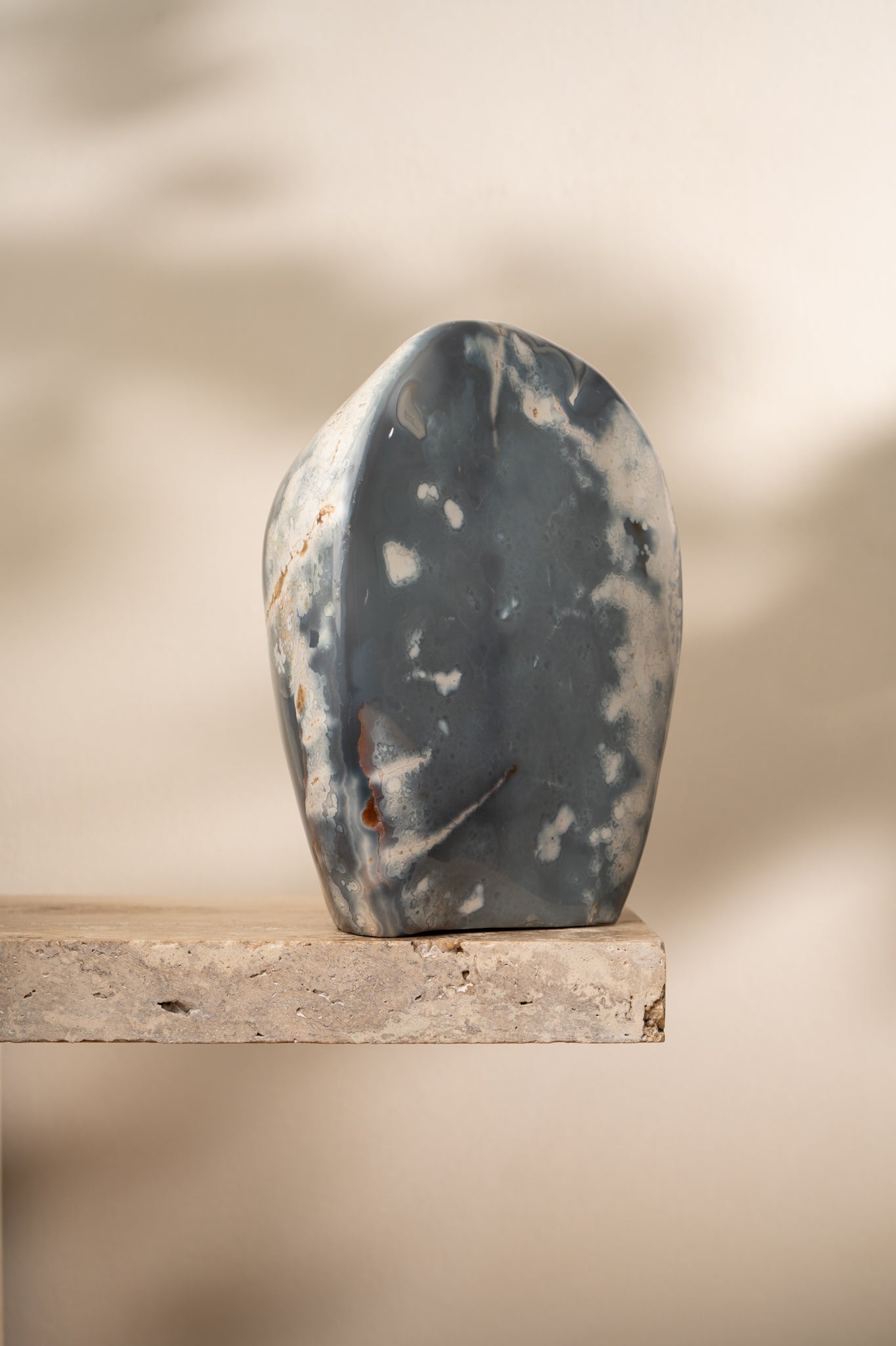 A polished Orca Agate freeform with soft blue, gray, and white banding, featuring smooth, flowing curves and unique natural patterns.
