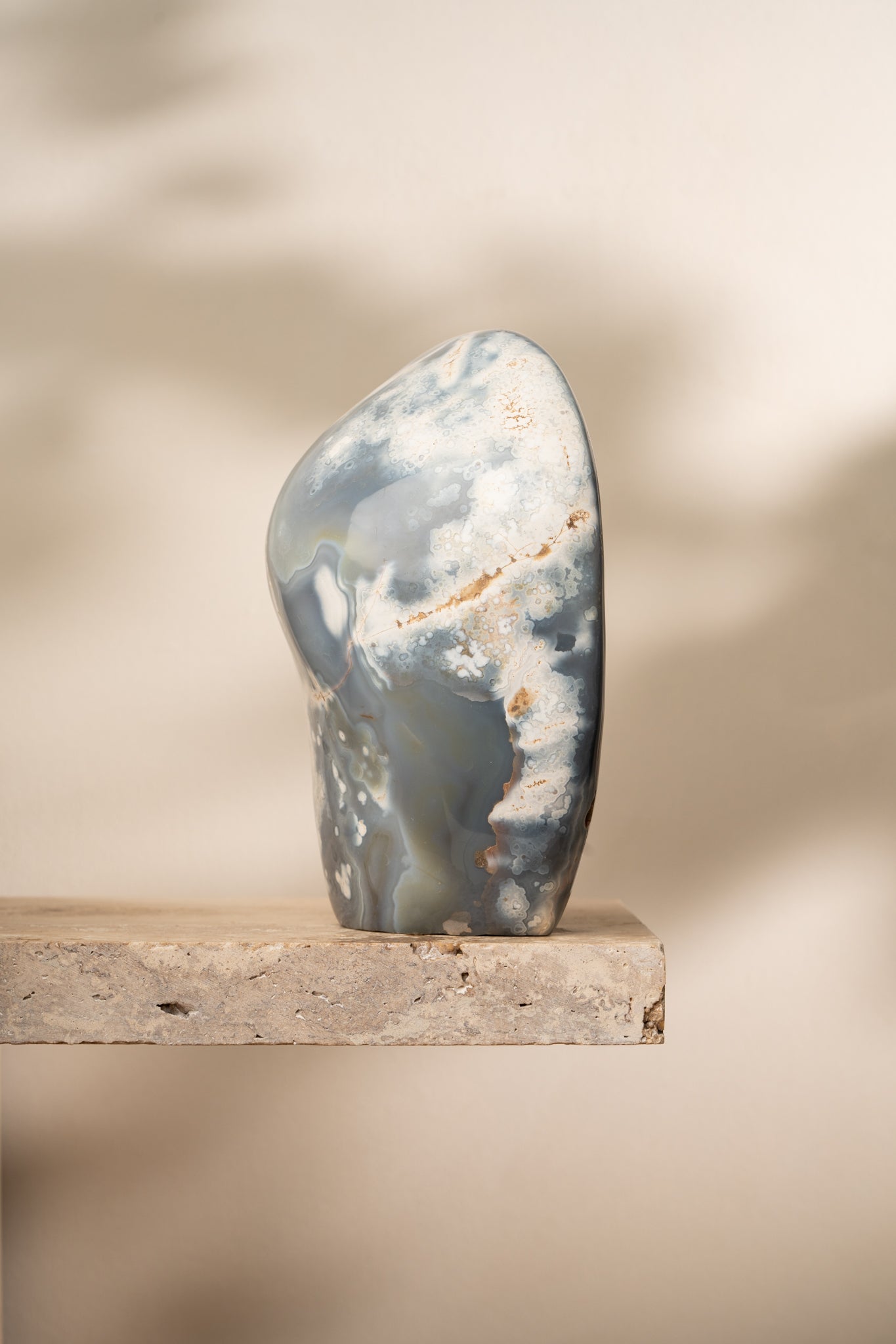 A polished Orca Agate freeform with soft blue, gray, and white banding, featuring smooth, flowing curves and unique natural patterns.