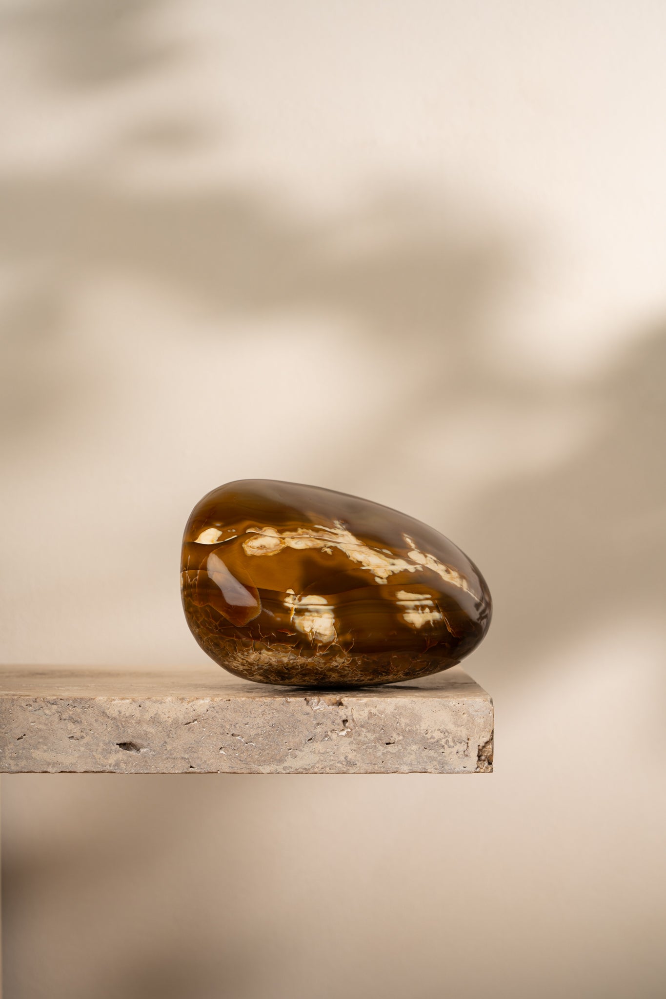 A polished Brown Agate freeform with deep brown and amber tones, featuring smooth, flowing lines and unique banding patterns.