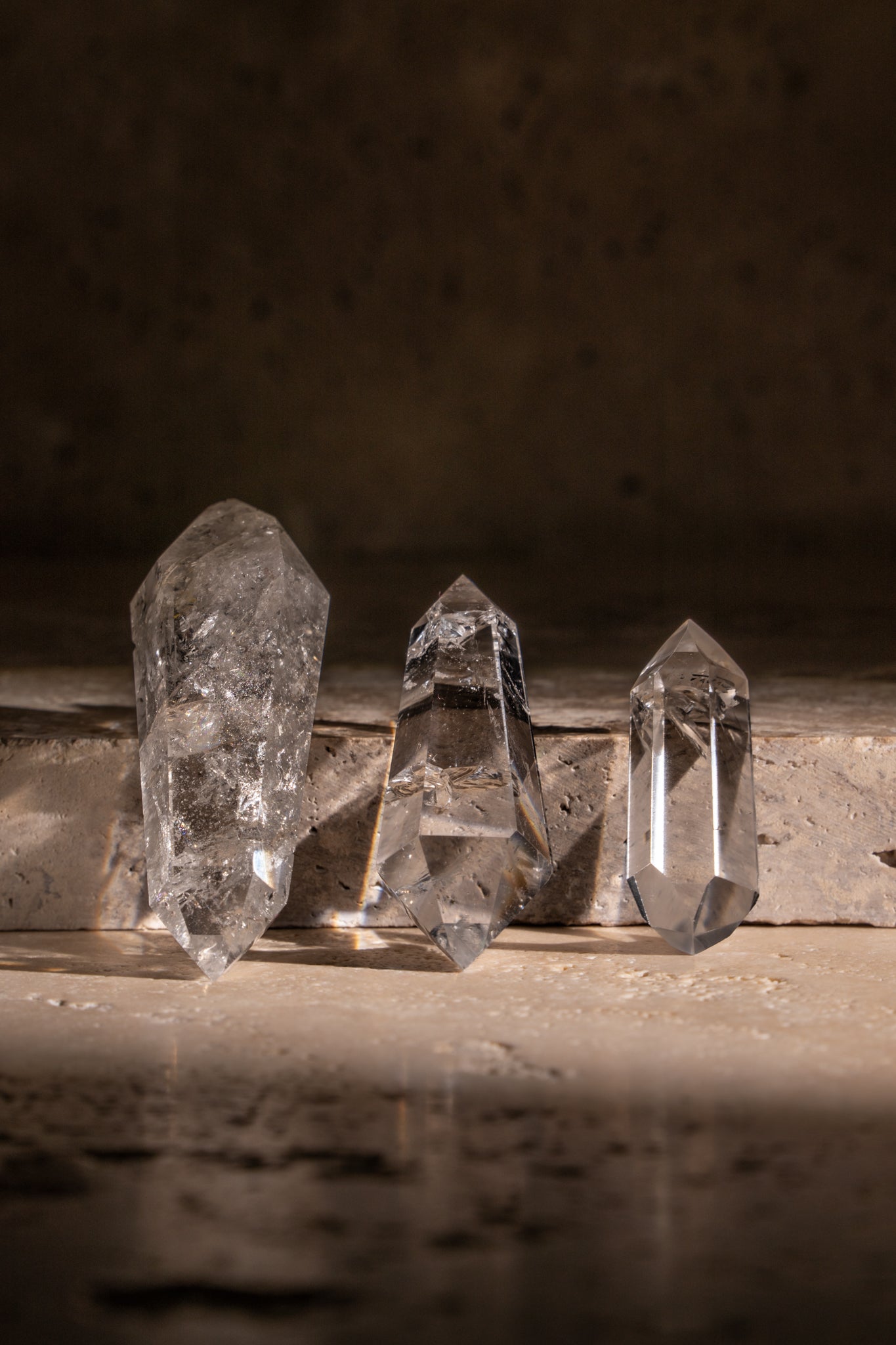 A set of three polished AAA quality Clear Quartz Double Terminated crystals with sharp, faceted tips on both ends, showcasing their exceptional clarity and natural inclusions.