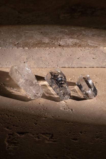 A set of three polished AAA quality Clear Quartz Double Terminated crystals with sharp, faceted tips on both ends, showcasing their exceptional clarity and natural inclusions.