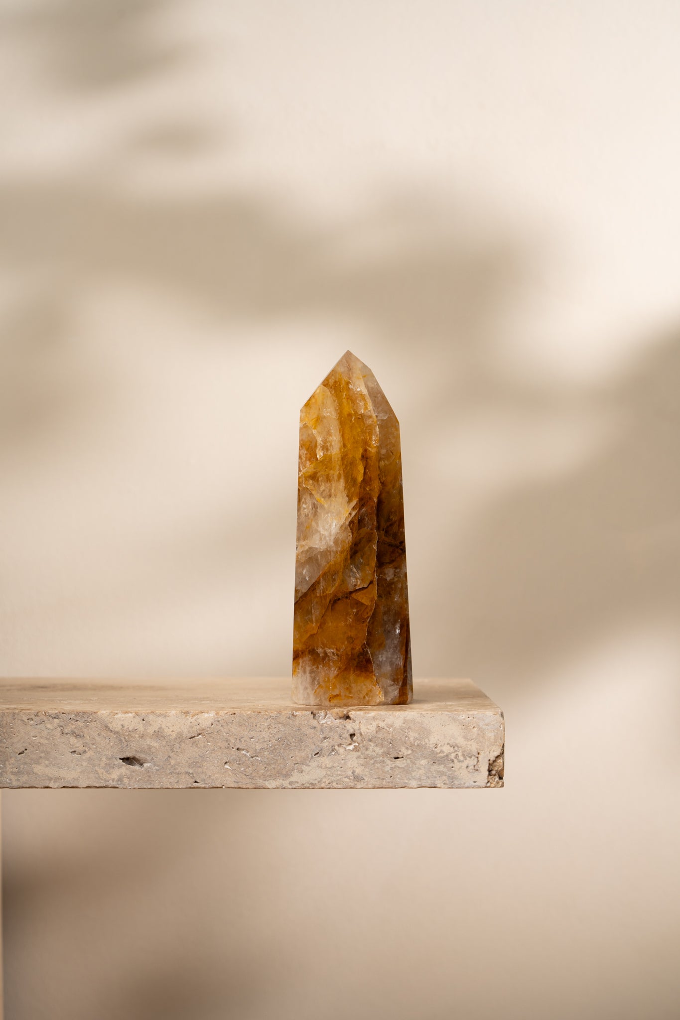 A polished Hematoid Quartz tower with golden, red, and clear hues, featuring smooth, faceted surfaces that taper to a pointed top.